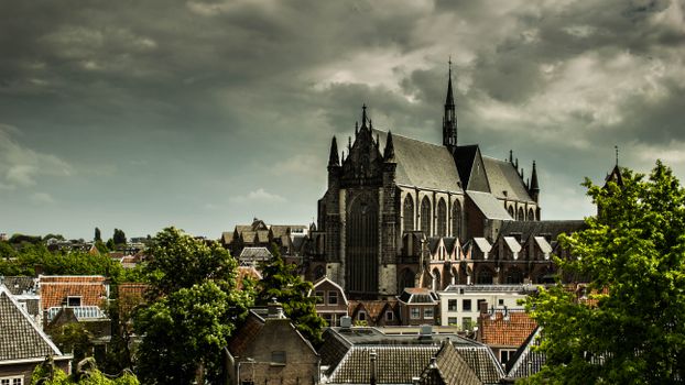 Noodweer boven Leiden Centraal met donkere onweerslucht, natte straten en bomen in harde wind