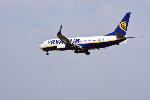 Passagiers wachten op een Ryanair-vlucht op een drukke luchthaven terwijl reisinformatie op schermen staat