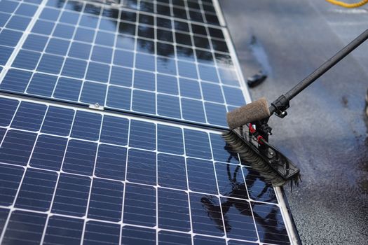 Huiseigenaar maakt zonnepanelen op een dak in Leiden voorzichtig schoon met een zachte borstel